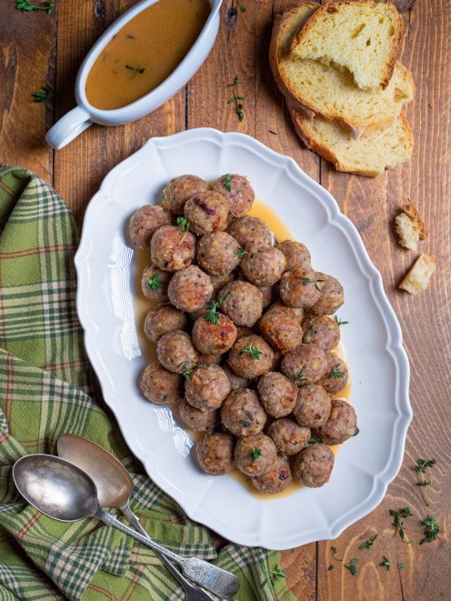 Polpette al forno dorate servite su vassoio con fondo di cottura e rametti di timo