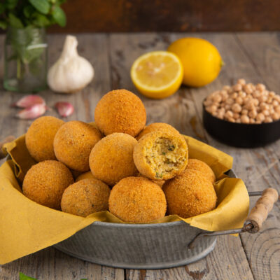 Polpette di ceci fritte dorate, una spezzata mostra il ripieno morbido con erbe aromatiche