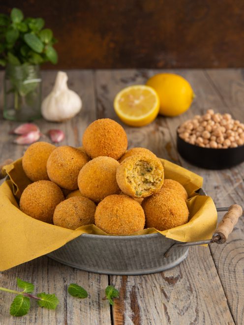 Polpette di ceci fritte dorate, una spezzata mostra il ripieno morbido con erbe aromatiche