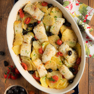 Baccalà e patate al forno con pomodorini, olive nere e prezzemolo tritato