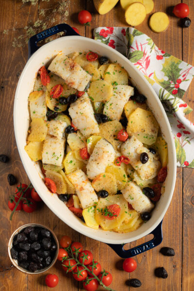 Baccalà e patate al forno con pomodorini, olive nere e prezzemolo tritato