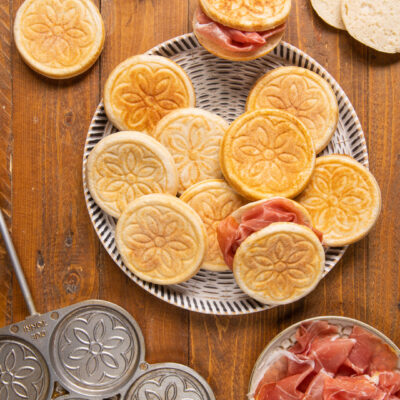 Tigelle con motivo floreale impresso, servite con fette di prosciutto crudo