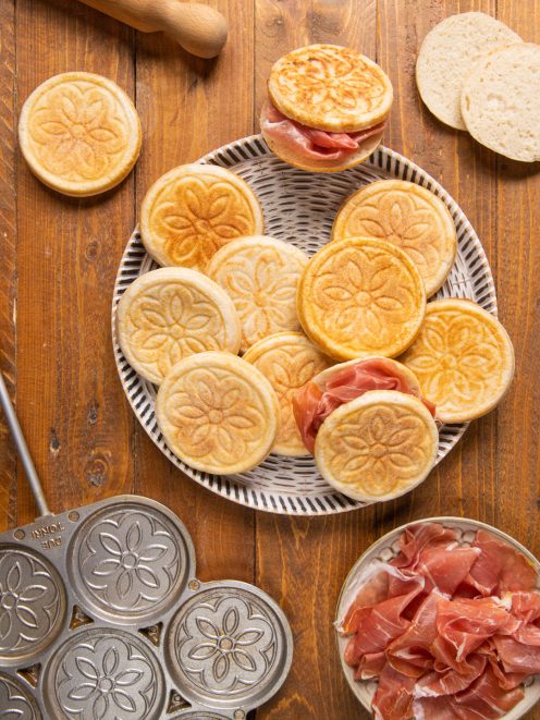 Tigelle con motivo floreale impresso, servite con fette di prosciutto crudo