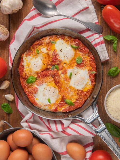Uova in purgatorio in padella con salsa di pomodoro, albumi cotti e foglie di basilico fresco