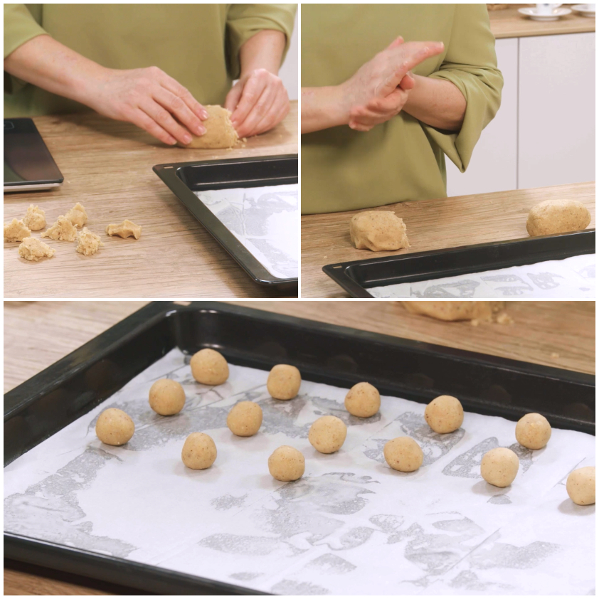 Palline di impasto per baci di dama disposte in fila su carta forno