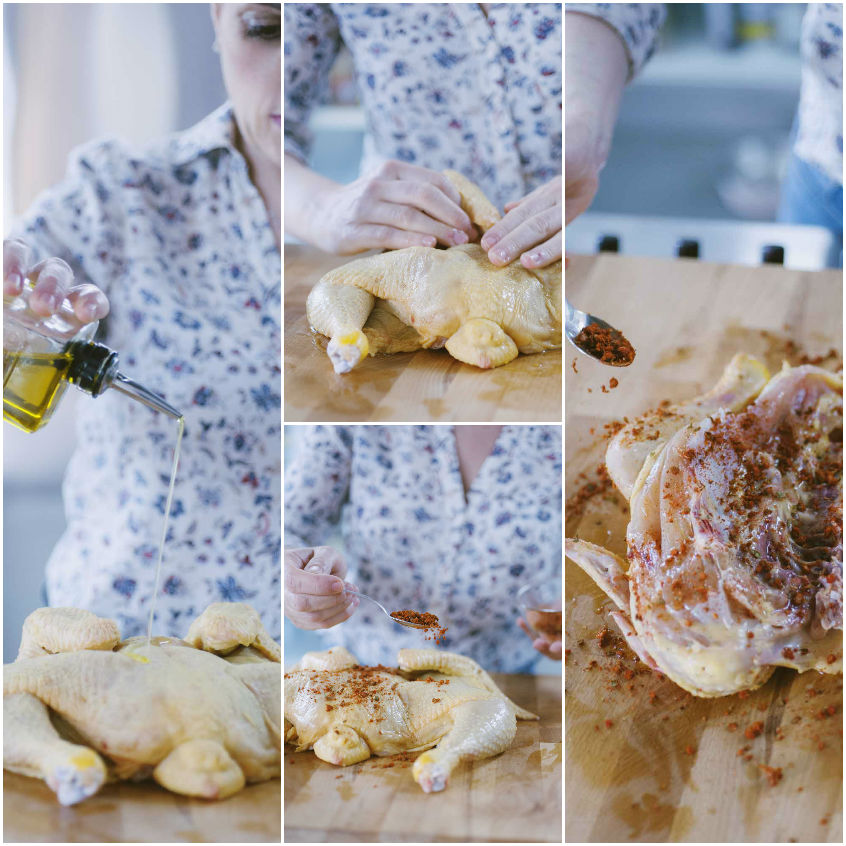 Mani che massaggiano il pollo alla diavola con erbe aromatiche e olio su tutta la superficie