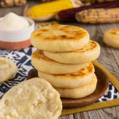 Arepas di mais impilate con superficie dorata e una spezzata che mostra l'interno morbido