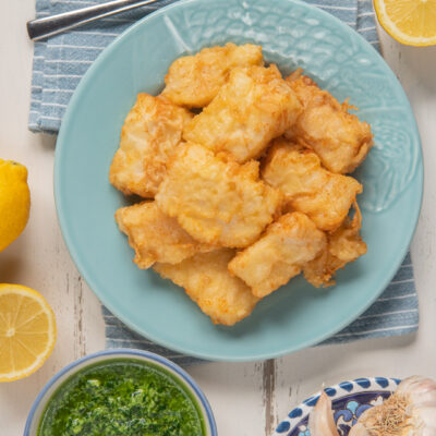 Baccalà fritto in pastella dorata servito con salsa verde al prezzemolo e aglio