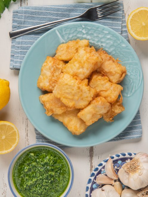 Baccalà fritto in pastella dorata servito con salsa verde al prezzemolo e aglio