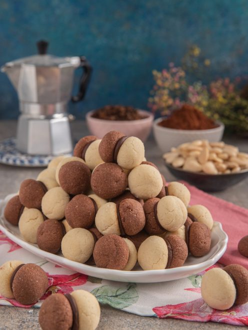 Baci di dama bigusto al cacao e nocciola impilati a piramide con ripieno di cioccolato fondente