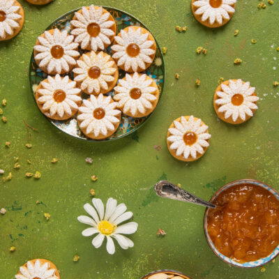 Biscotti margherita a forma di fiore con zucchero a velo e marmellata di albicocche al centro