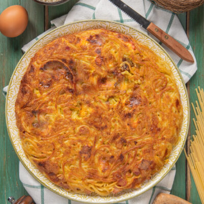 Frittata di spaghetti dorata e croccante in superficie, con uova e formaggio grattugiato