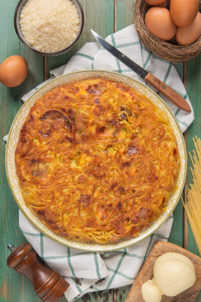 Frittata di spaghetti dorata e croccante in superficie, con uova e formaggio grattugiato