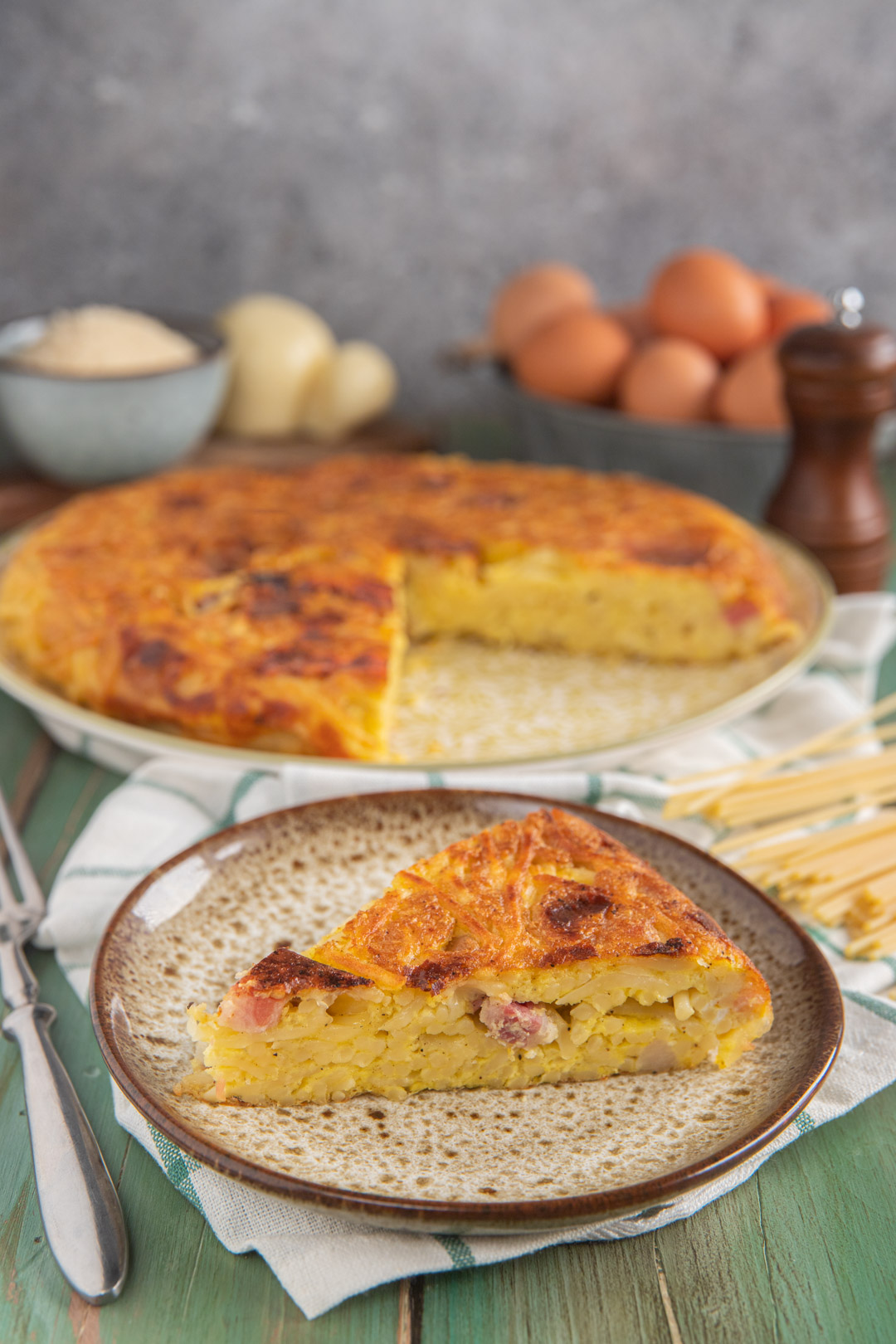 Frittata di spaghetti dorata e compatta, con una fetta già tagliata che mostra il ripieno