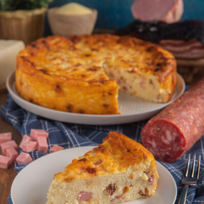 Migliaccio salato con una fetta tagliata che mostra il ripieno con salame e prosciutto