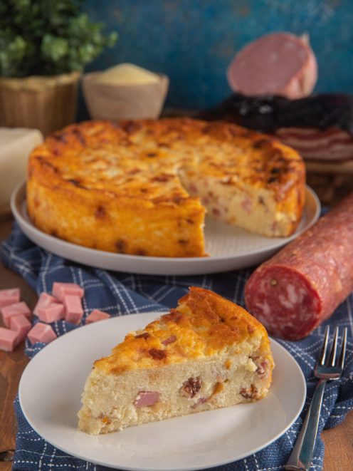 Migliaccio salato con una fetta tagliata che mostra il ripieno con salame e prosciutto