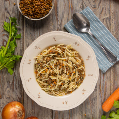 Pasta e lenticchie in brodo con carote e sedano, servita in un piatto fondo