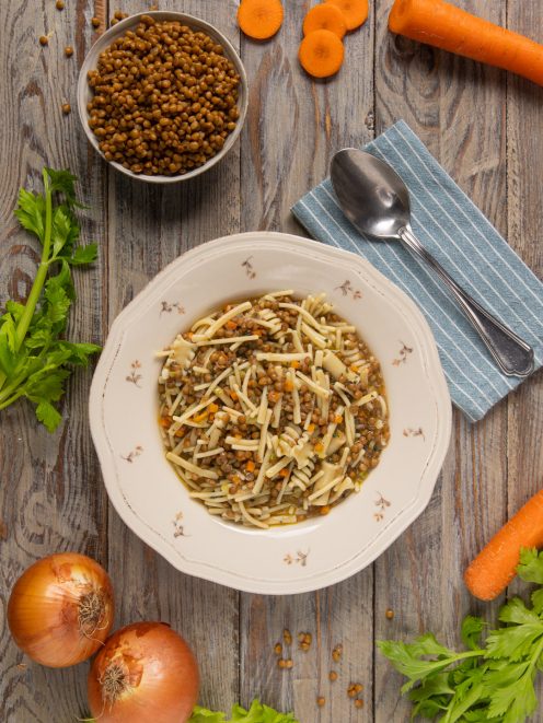 Pasta e lenticchie in brodo con carote e sedano, servita in un piatto fondo