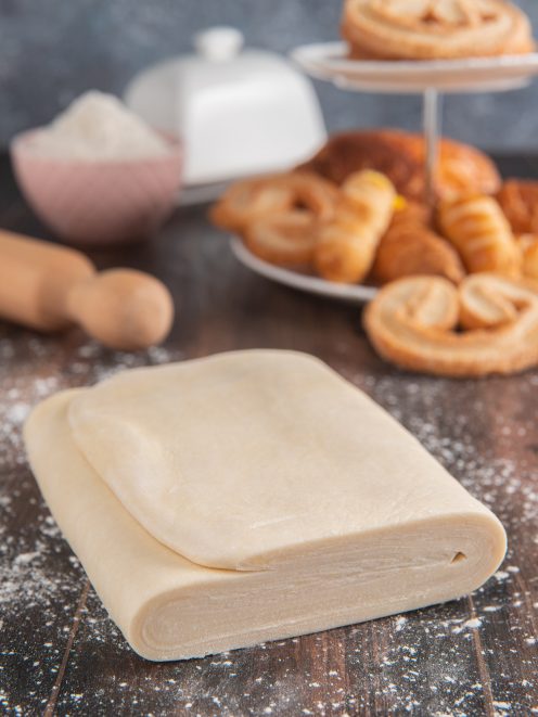 Pasta sfoglia cruda piegata a libro su piano infarinato, pronta per essere lavorata