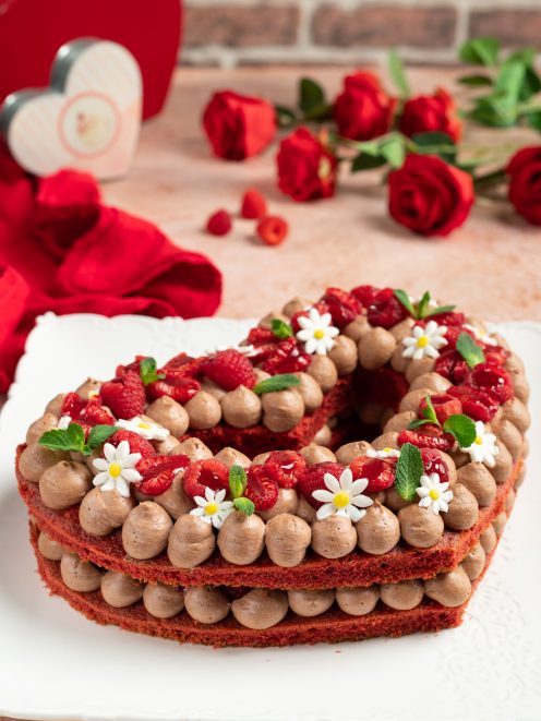 Red velvet cream tart a forma di cuore con ciuffi di crema al cioccolato, lamponi e fragole fresche