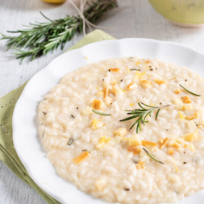 Risotto al limone e rosmarino con provola a cubetti e un rametto fresco in superficie