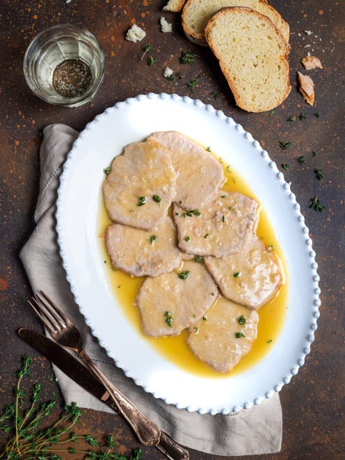 Scaloppine al vino bianco con salsa dorata e timo fresco, servite su vassoio ovale