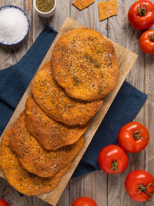 Schiacciatine al pomodoro e origano con sale grosso in superficie, disposte su tagliere