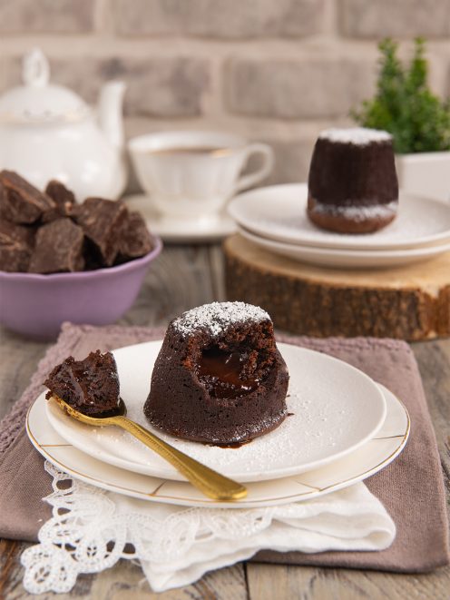 Tortino al cioccolato con cuore fondente spolverato di zucchero a velo e cucchiaio dorato
