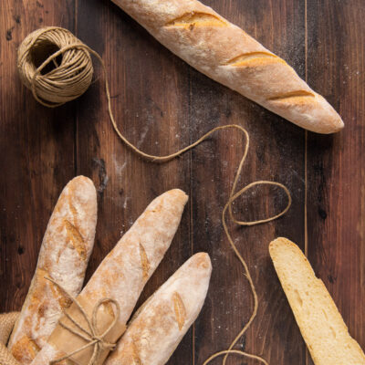 Baguette croccanti con crosta dorata e incisioni, una tagliata a metà per mostrare la mollica