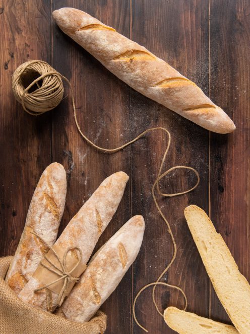 Baguette croccanti con crosta dorata e incisioni, una tagliata a metà per mostrare la mollica
