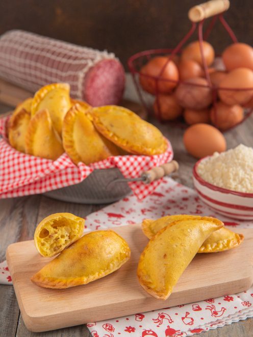 Calascione laziale dorato con la pasta sfogliata in primo piano, uno spezzato rivela il ripieno