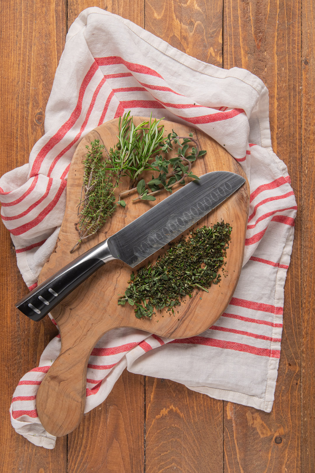 Erbe aromatiche fresche e tritate grossolanamente su un tagliere di legno con coltello