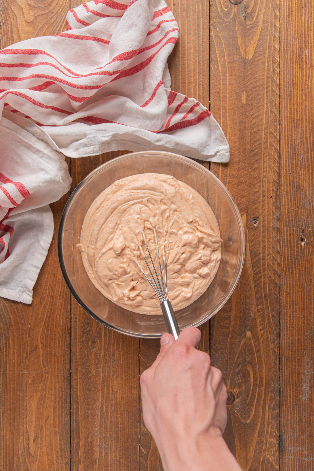 Mano mescola con una frusta la crema rosata di ricotta e peperoni in una ciotola