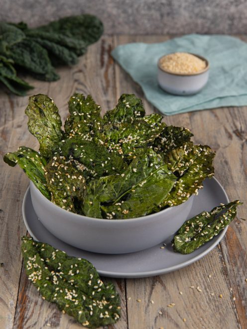 Chips di cavolo nero croccanti cosparse di semi di sesamo servite in ciotola