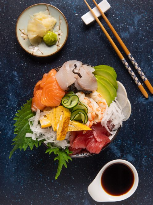 Chirashi con salmone, tonno, gamberi e avocado su daikon e foglie di shiso