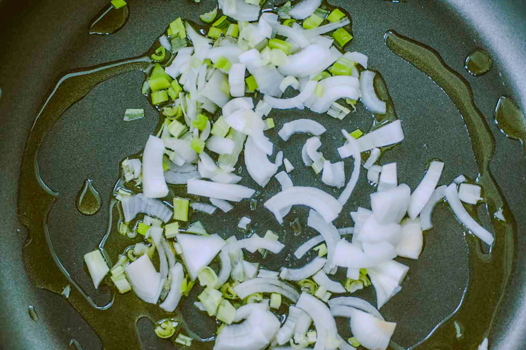 Cipollotto fresco tritato che appassisce in olio d'oliva in padella