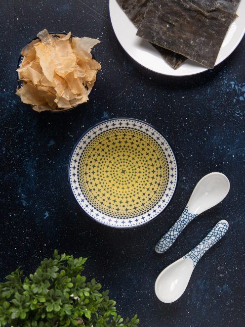 Ingredienti per il dashi con alghe kombu, fiocchi di katsuobushi e brodo dorato in ciotola