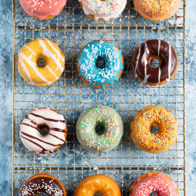 Donuts colorati con glasse diverse e codette su griglia di raffreddamento
