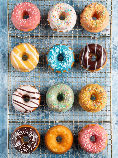 Donuts colorati con glasse diverse e codette su griglia di raffreddamento