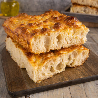 Focaccia bollosa tagliata a fette impilate che mostrano l'alveolatura soffice e la crosta dorata