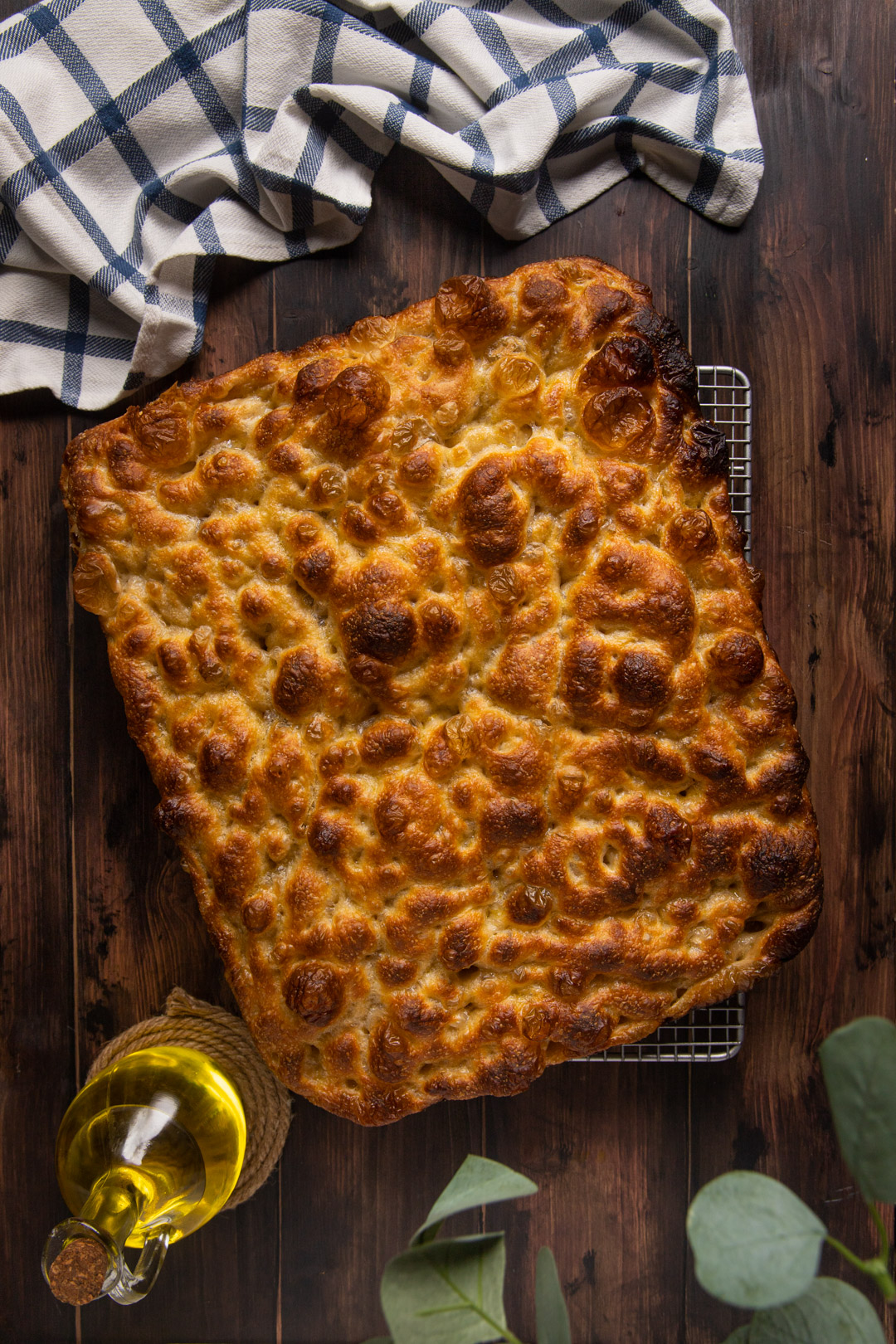 Focaccia bollosa dorata appena sfornata su una griglia, superficie alveolata e croccante