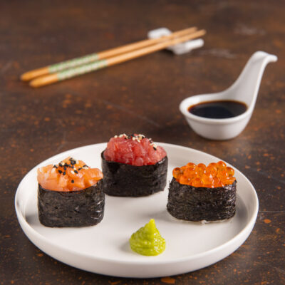 Tre gunkan maki con salmone, tonno e uova di salmone, serviti con wasabi