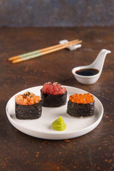 Tre gunkan maki con salmone, tonno e uova di salmone, serviti con wasabi