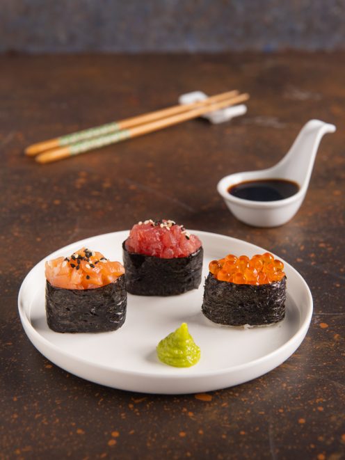 Tre gunkan maki con salmone, tonno e uova di salmone, serviti con wasabi