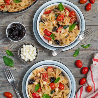 Insalata di pasta con farfalle, tonno, pomodorini, olive nere, mozzarella e basilico fresco