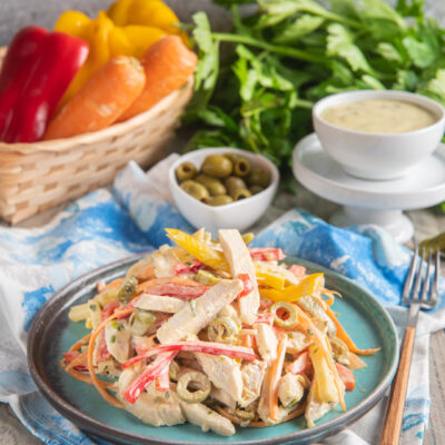 Insalata di pollo con strisce di peperone, carote julienne, olive verdi e salsa cremosa