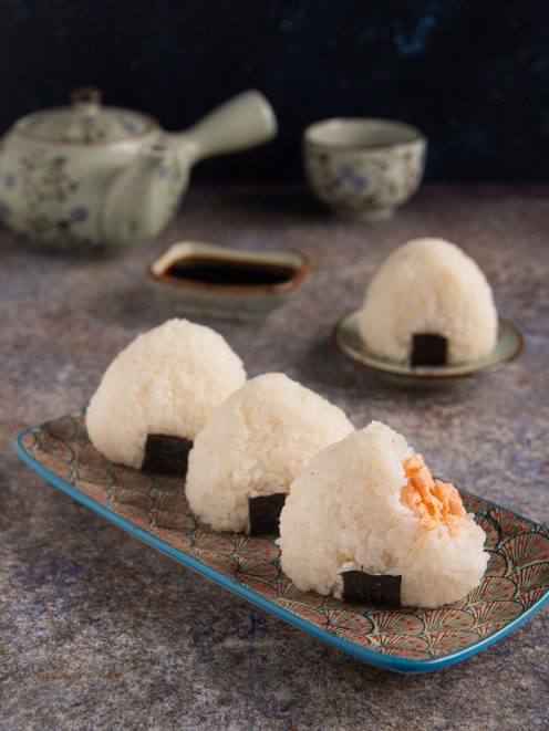 Gli onigiri sono una tipologia di sushi costituita da polpette di riso a forma triangolare con un ripieno di salmone e parzialmente avvolte da una striscia di alga Nori che le rende facili da mangiare con le mani