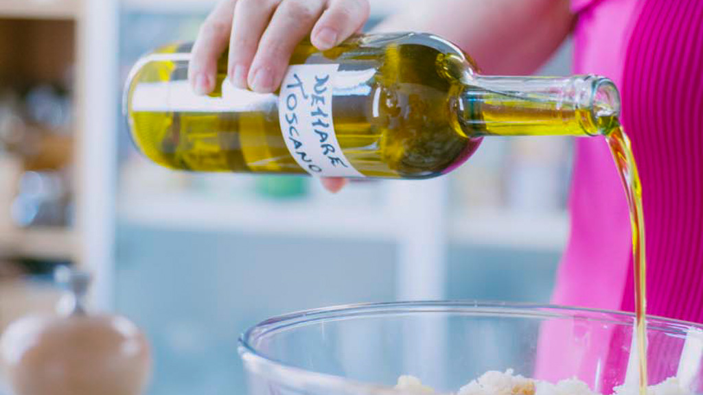 Olio extravergine versato a filo sul pane ammollato per condire la panzanella