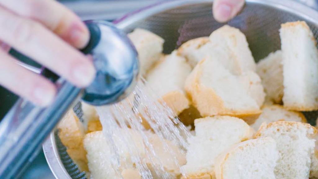 Pane raffermo a pezzi inumidito con un getto d'acqua a pioggia per la panzanella