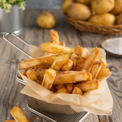 Patatine fritte dorate e croccanti servite in cestino con carta da forno